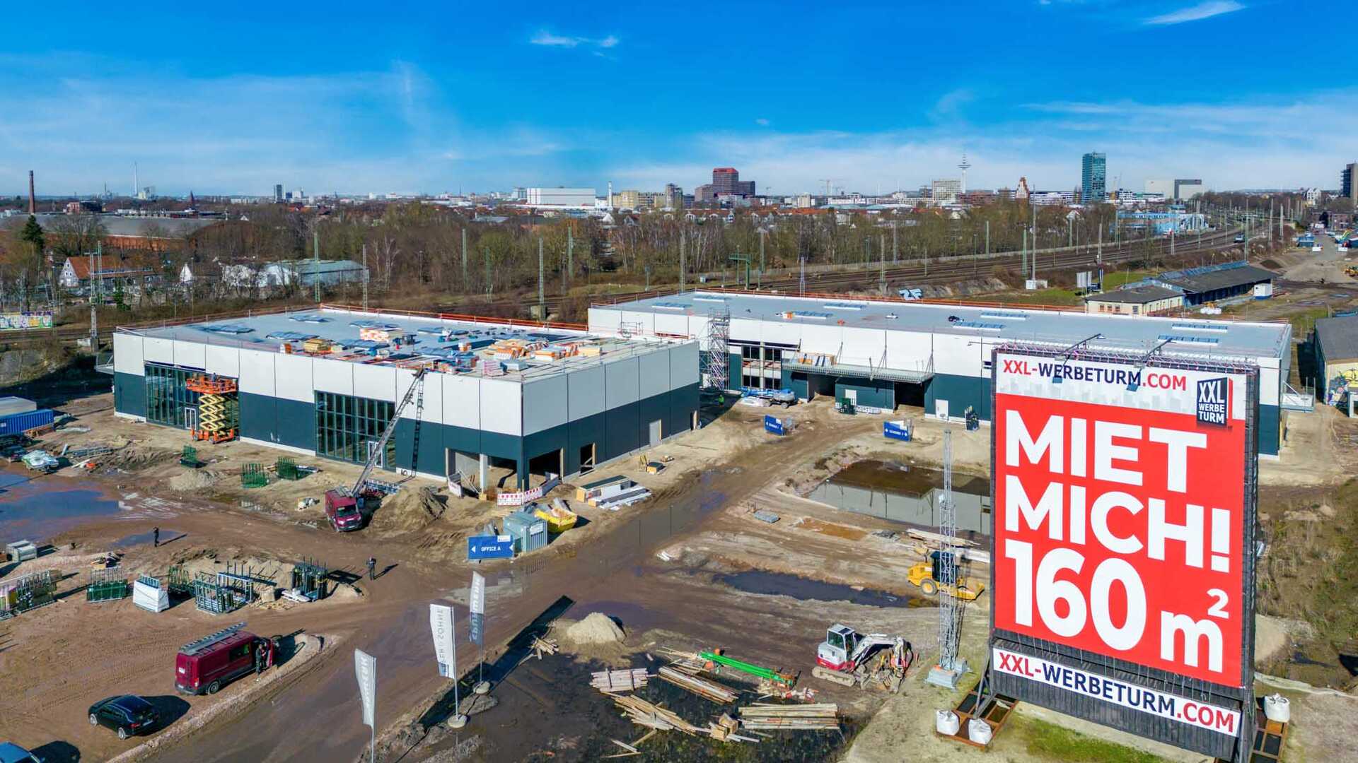 Photo from the construction phase of the railway track complex. The photo shows two buildings with several construction vehicles in front of them.